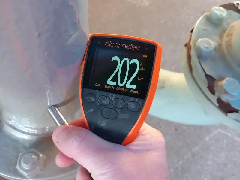 Applicator carrying out dft checks on the primer coat